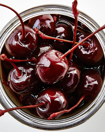 A jar filled with fresh, red bourbon cocktail cherries.